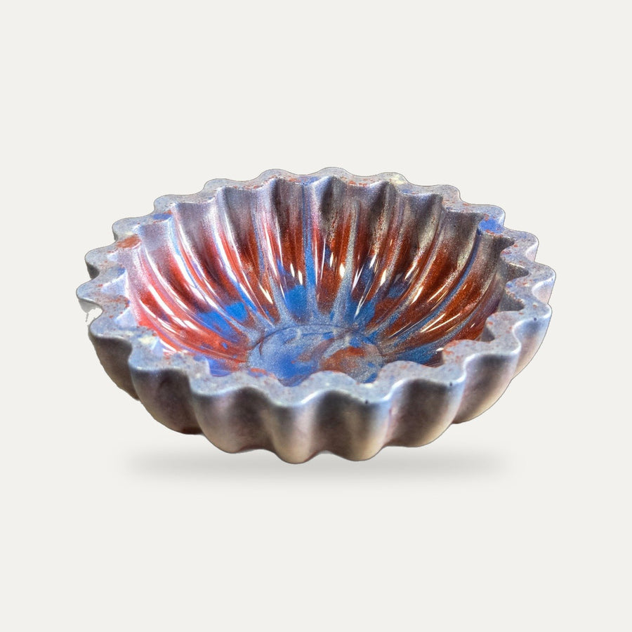 Fluted resin bowl swirled with cranberry, cobalt, and pearl